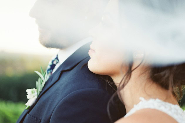Close-up of a bride and groom at a wedding, focusing on their profiles and attire.