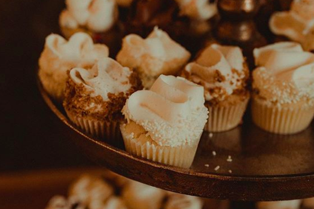 Assorted cupcakes with white frosting on a dark tray at Maysara Events.