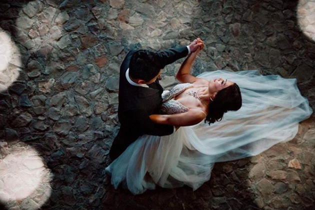 Bride and groom dancing on a stone floor during their wedding celebration.