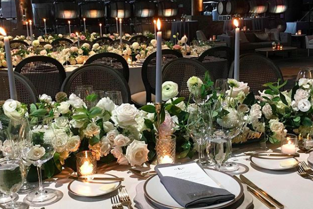 Elegant wedding table setup with white flowers, candles, and fine tableware at Maysara Events.