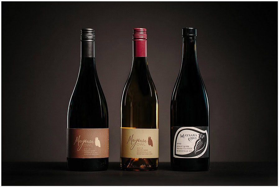 Three wine bottles with different labels on a dark background, showcasing wine packaging.